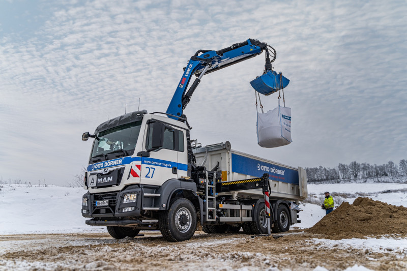 Ein Kranwagen gebt einen gefüllten Bigbag an