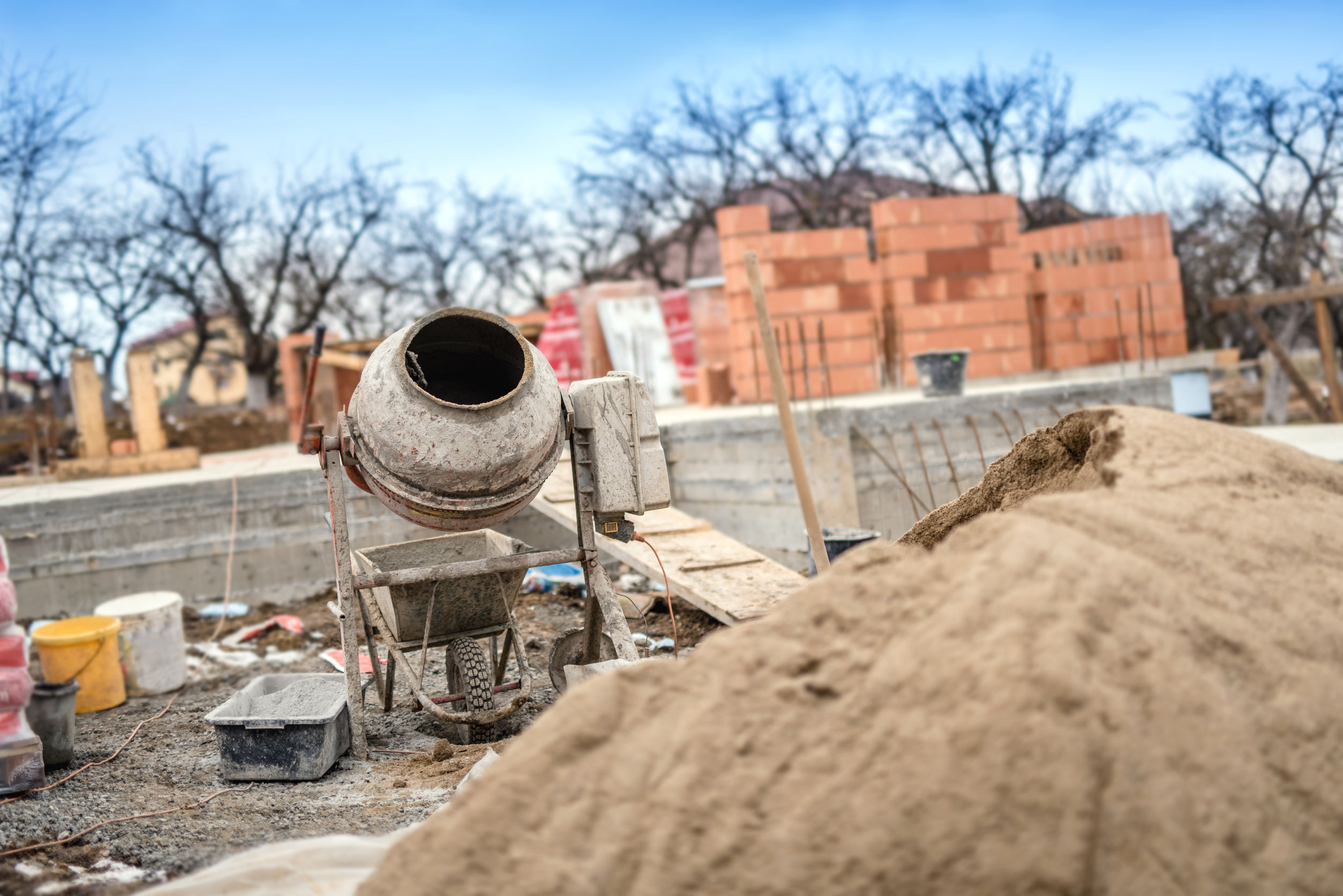 Betonmischer hinter einem Sandhaufen