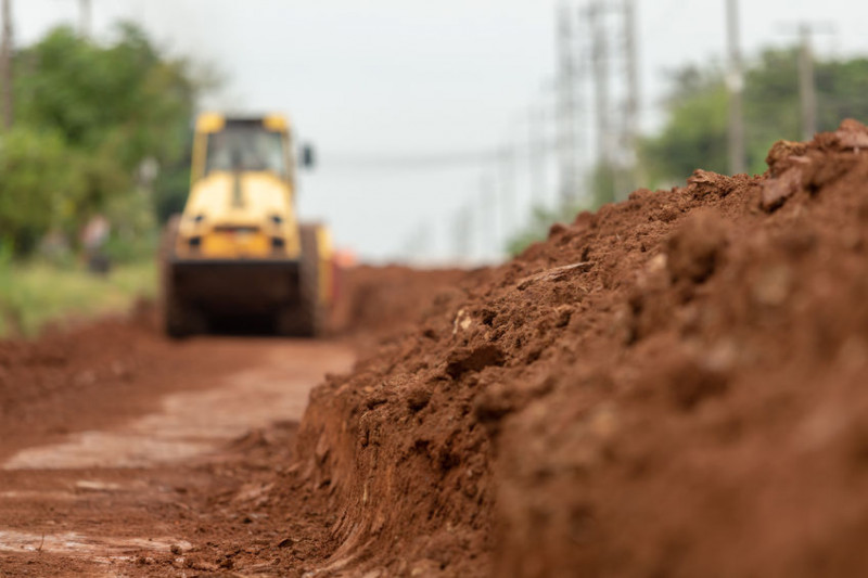 Bodenentsorgung und umweltgerechte Entsorgung von Erdmaterialien auf Baustellen Abbildung von Boden im Hintergrund eine Walze